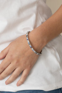 Featuring regal emerald style cuts, a dainty row of purple, white, and blue rhinestones are encrusted across the front of a silver cuff-like bangle for a timeless fashion. Features a hinged closure.  Sold as one individual bracelet.