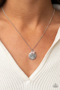 A dainty cluster of opaque pink beads delicately joins a shiny silver disc stamped in the word, 