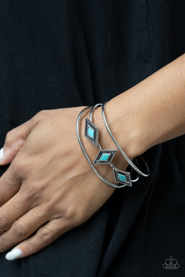 Featuring turquoise stones, a trio of diamond shaped antiqued silver studded frames, line up across the center of layered silver bands creating a striking display atop a silver cuff.  Sold as one individual bracelet.