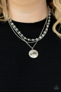 Infused with a strand of iridescent crystal-like beads, two dainty rows of mismatched silver chains delicately layer below the collar. Stamped in the word, 