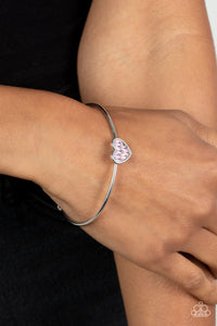 Brimming with dainty emerald-cut pink rhinestones, a simple silver heart frame sits atop a classic silver bar curved into a simple cuff bracelet for a whimsical display across the wrist.  Sold as one individual bracelet.