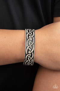 A black leather band is etched in a runic-like pattern, creating a rustic centerpiece around the wrist. Features an adjustable snap closure.  Sold as one individual bracelet.