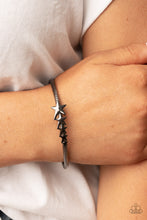 Load image into Gallery viewer, Glistening gunmetal stars graduate in size across the center of a textured gunmetal bangle, creating a stackable stellar centerpiece around the wrist.  Sold as one individual bracelet.