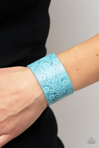 A flowery and leafy motif blooms across the front of a distressed blue leather band, resulting in a rustic floral centerpiece around the wrist. Features an adjustable snap closure.  Sold as one individual bracelet.