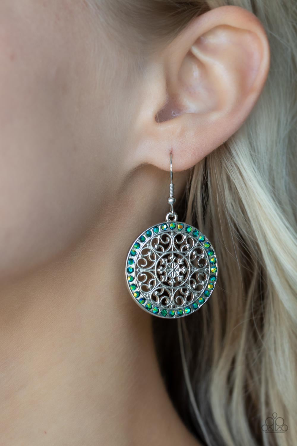 Infused with a border of iridescent green rhinestones, studded silver heart shape filigree fans out from a decorative silver floral center for a whimsical look. Earring attaches to a standard fishhook fitting.  Sold as one pair of earrings.